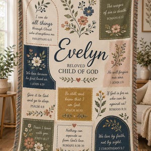 May include: A woven throw blanket featuring the name Evelyn and the phrase Beloved Child of God, surrounded by various Bible verses in rectangular panels. The design includes floral illustrations in muted tones of blue, green, and pink.