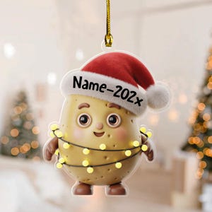 May include: A Christmas ornament featuring a cartoon potato character wearing a Santa hat and a string of lights. The text "Name-202x" is printed on the hat. The ornament is suspended by a gold string.