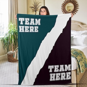 May include: A green and black fleece blanket with the text "Team Here" on both sides. The blanket is divided diagonally with a white stripe.