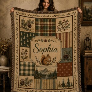 May include: A woven throw blanket featuring a patchwork design with forest-themed motifs including pine trees, pinecones, berries, and a mountain landscape. The center panel displays the name Sophia above a squirrel illustration with a fringed edge.