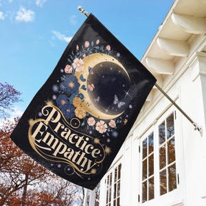 May include: A black garden flag with a crescent moon and floral design. The text "Practice Empathy" is written in gold lettering.