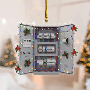 May include: A Christmas ornament shaped like an electrical panel, with the text "Name 202X". The panel is decorated with holly, a string of colorful lights, and a gold hanging cord. The panel doors are open, revealing colorful wires and circuit breakers.