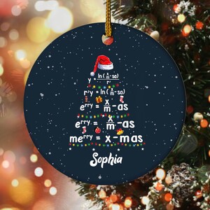 May include: A navy blue Christmas ornament with a gold string. The ornament features a Christmas tree design made of mathematical equations and the text "Sophia" at the bottom. A Santa hat is at the top.