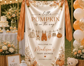 May include: A vertical cream-colored fabric banner featuring the text A little PUMPKIN is on the way! and WELCOME TO Madison's BABY SHOWER OCTOBER 18, 2026. The design includes illustrations of baby clothes, a rabbit, pumpkins, and autumn leaves.