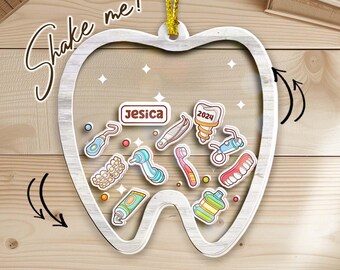 May include: A wooden tooth-shaped ornament with a gold string for hanging. Inside the tooth shape are various dental-themed stickers, including a toothbrush, toothpaste, and dental tools. The name "Jesica" is displayed, along with the text "Shake me!"