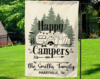 May include: A beige garden flag with a black and white illustration of a camper van in a forest setting. The text "Happy Campers" is above the camper van, and the text "the Smiths Family" is below the camper van. The text "MARRYVILLE, TN" is at the bottom of the flag.