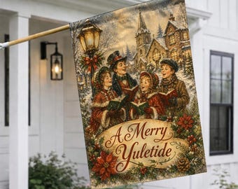 May include: A rectangular garden flag featuring a winter scene with three carolers singing from songbooks near a streetlamp and a church. The text A Merry Yuletide is printed in a decorative script font over a wreath of poinsettias and pinecones.