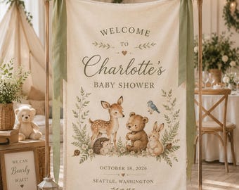 Peut inclure: Une bannière en tissu crème suspendue à un cadre en bois avec des rubans vert sauge. Le texte indique Welcome to Charlotte's Baby Shower, October 18, 2026, Seattle, Washington. Les illustrations montrent un cerf, un ours, un lapin, un hérisson et un oiseau.