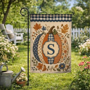 May include: A rectangular garden flag featuring a central pumpkin illustration with a blue letter S inside a decorative frame. The pumpkin has vertical segments in blue gingham, orange plaid, and floral patterns, surrounded by autumn leaves and berries.