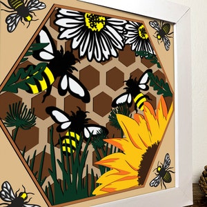 K&ouml;nnte beinhalten: Eine Papierkunst mit einem Wabenmuster, Bienen, G&auml;nsebl&uuml;mchen und einer Sonnenblume. Die Bienen sind gelb und schwarz mit wei&szlig;en Fl&uuml;geln. Die Blumen sind wei&szlig; und gelb. Die Wabe ist braun.