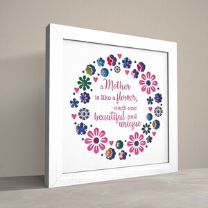 May include: White framed print with a pink, blue, and green floral design. The text reads "A Mother is like a flower, each one beautiful and unique."