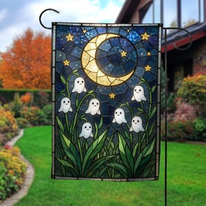 May include: A rectangular garden flag featuring a stained glass style design of a glowing yellow crescent moon and golden stars against a dark blue night sky, with six small white ghost figures emerging from green lily of the valley flowers.