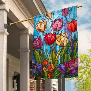 May include: A colorful stained glass style flag featuring a bouquet of tulips in shades of red, yellow, purple, and pink. The tulips are arranged in a vase with green leaves and stems. The background is a light blue.
