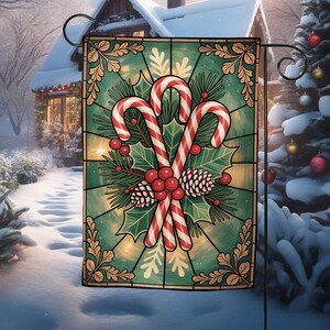May include: A Christmas garden flag featuring a stained-glass design with candy canes, holly, pinecones, and berries. The flag has a green background with gold accents and is displayed outdoors in a snowy setting.