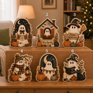 May include: Six decorative wooden ghost ornaments numbered one through six. Each features a white ghost with autumn-themed elements like pumpkins, leaves, and lanterns. Designs include text such as BOO, Stay Spooky, Happy Halloween, and Spells & Giggles.