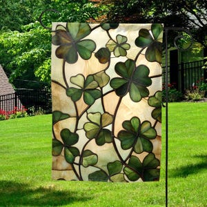 May include: A garden flag with a stained glass design of green four-leaf clovers on a cream background.