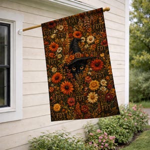 May include: A rectangular garden flag featuring a black cat wearing a pointed witch hat, surrounded by a dense pattern of orange, yellow, and red autumn flowers. The letters FDT are repeated across the floral background in a dark brown font.