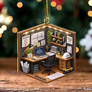 May include: A hexagonal ornament featuring a miniature engineering office scene with a desk, chair, computer, blueprints, and a white hard hat. The name Jason is printed on the bottom edge. The walls display signs reading Engineer Design Build Solve Repeat and Engineering Tomorrow Today.