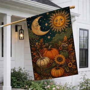 May include: A rectangular garden flag featuring a dark blue night sky with a crescent moon and a sun with a face, above a scene of orange and green pumpkins in a wooden crate, surrounded by autumn leaves, sunflowers, and red berries.