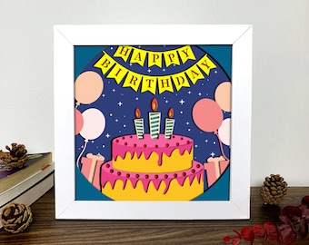May include: A framed, layered paper art piece featuring a two-tiered birthday cake with three lit candles. The cake is pink and yellow, with a banner that reads "HAPPY BIRTHDAY". Pink and peach balloons and gifts are also included.