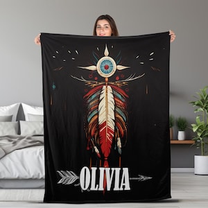 May include: Black fleece blanket with a colorful Native American inspired design featuring a feather, an arrow, and the name "Olivia".