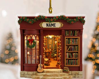 May include: A Christmas ornament shaped like a bookstore, with a red facade, a wreath, and a guitar. The sign above the door reads "NAME". The interior is lit with warm lights, and filled with books and a Christmas tree.