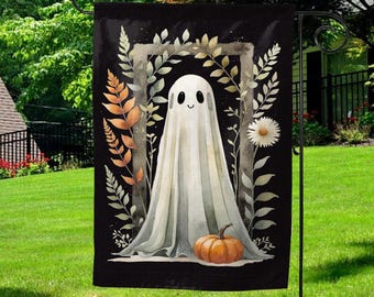 May include: A black Halloween garden flag featuring a friendly ghost with a pumpkin. The ghost is white with a smiling face, framed by a floral wreath. The flag is displayed on a black metal stand in a grassy yard.