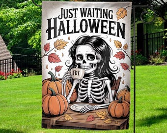 May include: Halloween garden flag featuring a skeleton with long black hair, drinking from a mug. The flag reads "Just Waiting Halloween" with pumpkins and fall leaves. The mug has the initials "FDT".