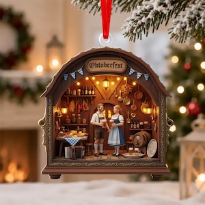 May include: A brown, arched, wooden-style Christmas ornament featuring a miniature Oktoberfest scene with two figures holding beer steins, a table with food, an accordion, and hanging kitchenware, topped with a red ribbon for hanging.