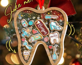 May include: A wooden tooth-shaped Christmas ornament with a clear center filled with small, colorful dental-themed charms. The ornament has the text "Shake me!" and includes a red ribbon for hanging. The ornament has the name "Benson" on it.