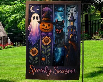 May include: A Halloween garden flag featuring a spooky design. The flag displays a ghost, jack-o'-lantern, black cat, and witch with a haunted house. The words "Spooky Season" are written across the bottom. The flag is displayed on a black metal stand.