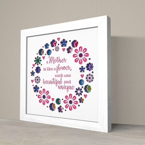 May include: White framed wall art with a pink and blue floral design and the text "a Mother is like a flower, each one beautiful and unique".