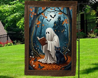 May include: Halloween garden flag featuring a ghost reading a book, with a black cat, bats, and a haunted house in the background. The flag has a dark brown frame and is set against a backdrop of trees with orange leaves.