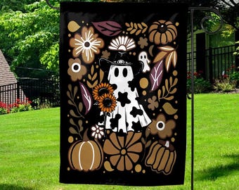 May include: Black garden flag featuring a whimsical Halloween design. A ghost wearing a cowboy hat and holding sunflowers is surrounded by pumpkins, flowers, and leaves in shades of brown, white, and orange.