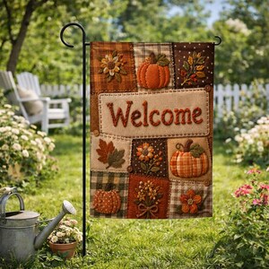 May include: A rectangular garden flag featuring a patchwork design with the word Welcome in raised orange letters. The flag displays various autumn-themed appliqués including orange pumpkins, brown and green leaves, and yellow flowers on fabric squares.
