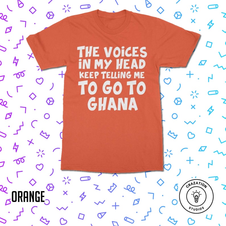 May include: Orange t-shirt with white text that reads "The Voices in My Head Keep Telling Me To Go To Ghana". The shirt is on a white background with a colorful pattern.