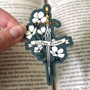 May include: A green and white sticker with a sword and flowers. The text "Fantasy Reader" is on a white banner.