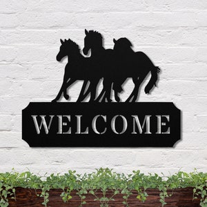 May include: Black metal silhouette of three horses running, with the word "WELCOME" on a rectangular sign below.