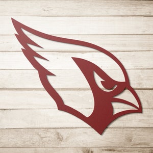 May include: A red metal silhouette of a cardinal bird's head with a wing on the left side. The silhouette is against a white wood background.