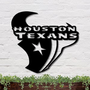 May include: Black metal wall art featuring the Houston Texans logo. The logo is a stylized silhouette of a bull's head with a star and the words "HOUSTON TEXANS" in a bold font.
