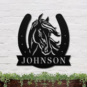 May include: Black metal horseshoe with a horse head silhouette in the center and the name "JOHNSON" on a banner below.