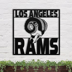 May include: Black metal wall art featuring a stylized ram's head with the text "Los Angeles Rams" in a bold font.