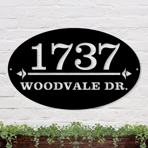 May include: Black oval metal house number sign with white lettering. The number 1737 is displayed above the text "WOODVALE DR."