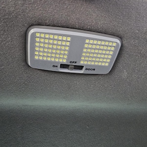 May include: A white LED light with a gray housing and a switch labeled "ON", "OFF", and "DOOR".