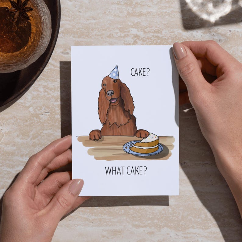 Puede incluir: Una tarjeta de felicitaci&oacute;n con una ilustraci&oacute;n de dibujos animados de un perro con un gorro de fiesta mirando un trozo de pastel. El texto de la tarjeta dice "Cake? What cake?"