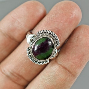 May include: A silver ring with a green and purple oval gemstone set in a decorative silver band.