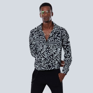 May include: A black long-sleeved shirt with a white abstract pattern. The shirt has a collar and a button-up front.