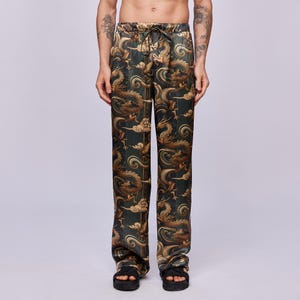 May include: Dark green pants with a repeating pattern of gold dragons and clouds. The pants have a drawstring waist and a relaxed fit. The fabric has a silky sheen. The pants are a unique and eye-catching piece of clothing.