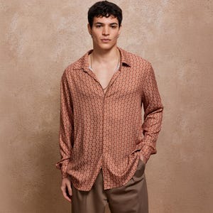 May include: A long-sleeved shirt with a brown and white geometric pattern. The shirt has a collared neckline and a button-up front.