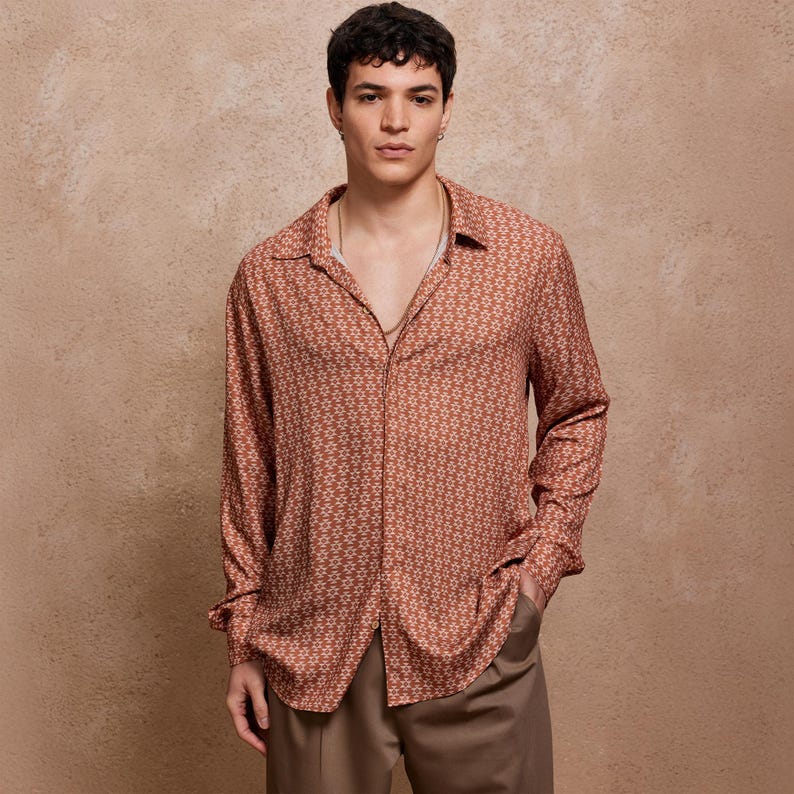 May include: A long-sleeved shirt with a brown and white geometric pattern. The shirt has a collared neckline and a button-up front.
